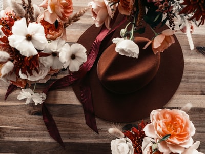 棕色的软呢帽旁边白色和粉红色的花
